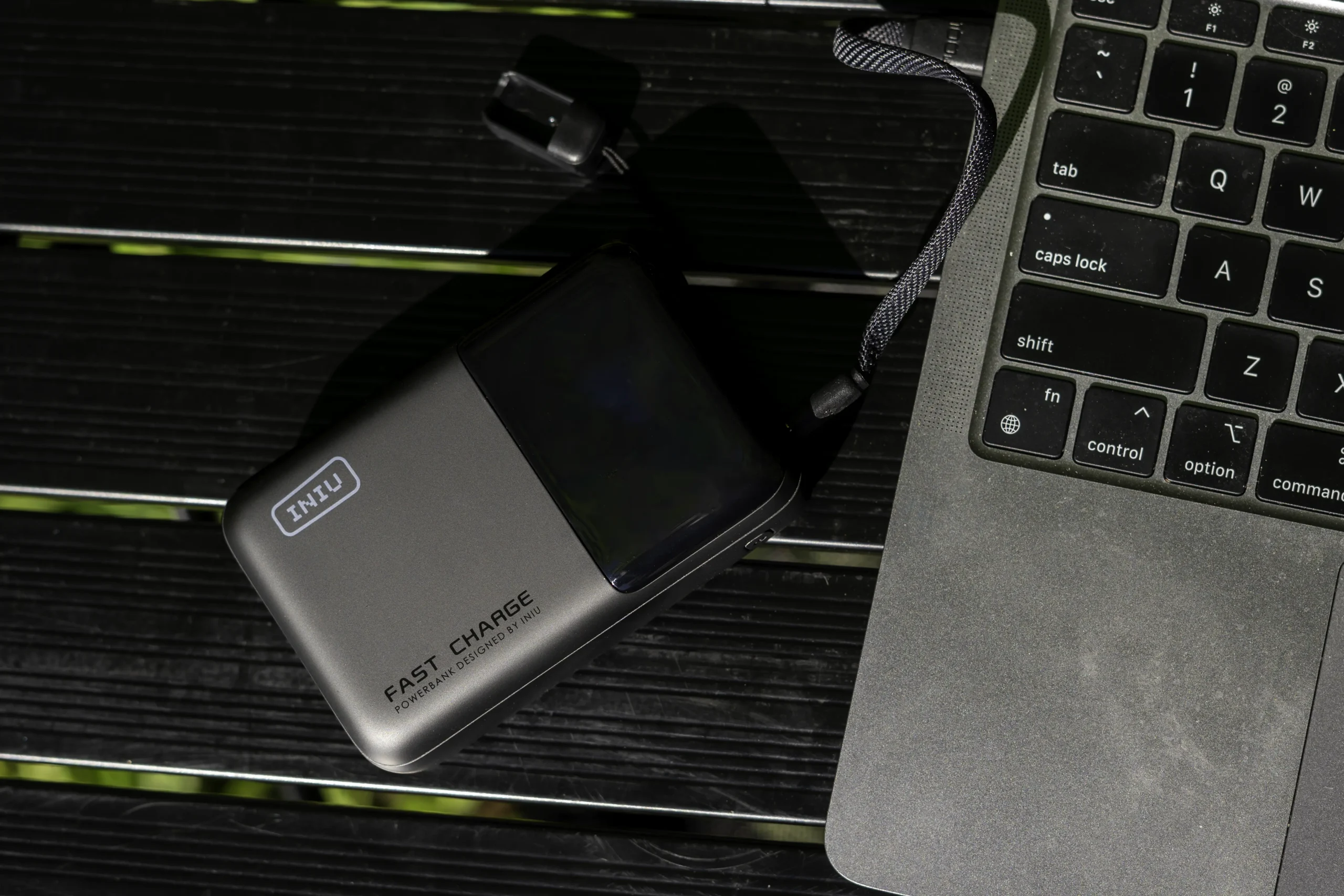 INIU Cougar P63 100W High Capacity Laptop Power Bank | 25000mAh next to a silver laptop on a black table.