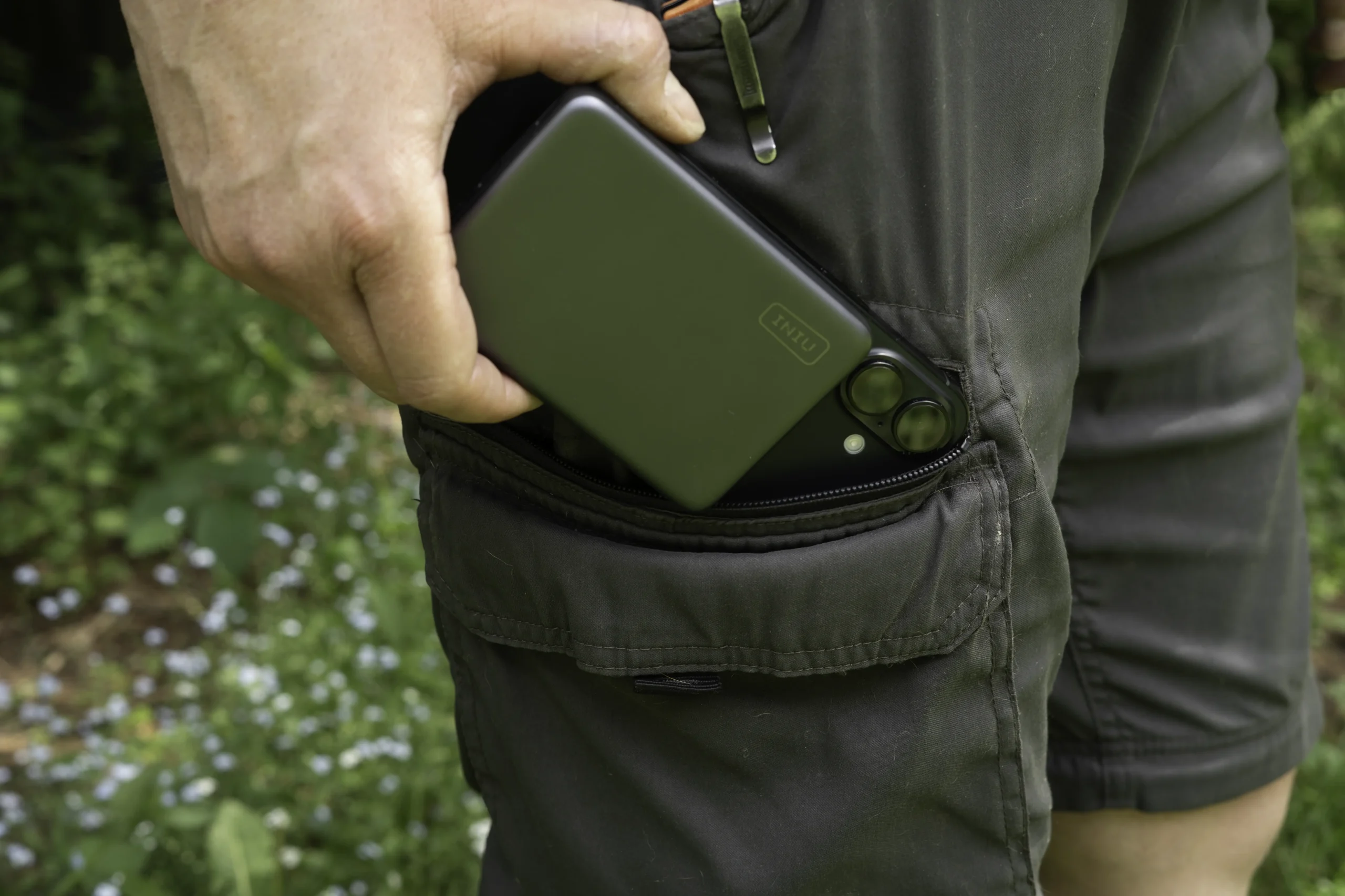 A silver INIU SnapGo Air P781 attached to an iPhone being removed from a cargo pocket.